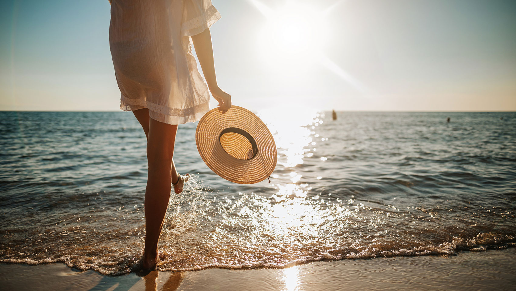Woman walking on beach with sun hat