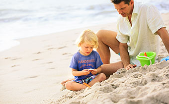 Dad watched son dig in the sand on the beach